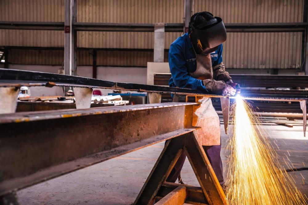 A welder works on a heavy metal steel structure