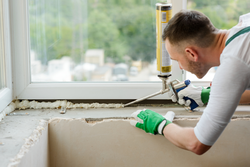 A builder caulking a window